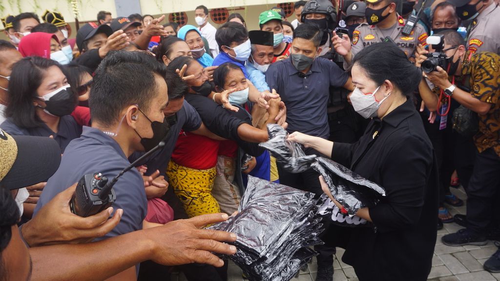 Ketua DPR Puan Maharni (kanan) membagikan kaus kepada para pedagang di Pasar Legi, Kota Surakarta, Jawa Tengah, Kamis (20/1/2022), Aksi itu dilakukan seusai meresmikan salah satu pasar tradisional terbesar di kota tersebut. Pasar dibangun kembali akibat kebakaran pada 2018.