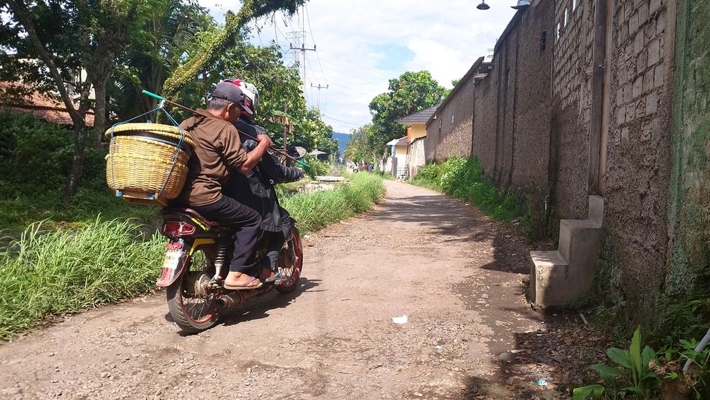 Warga melintasi salah satu akses jalan menuju Kampung Babakan Mande, Desa Gunungsari, Kecamatan Ciranjang, Kabupaten Cianjur, Jawa Barat, Minggu (22/1/2023). Meski berlubang, berbatu, dan minim penerangan, sebagian besar warga memilih jalan itu lantaran dianggap lebih dekat. Menurut warga sekitar, kondisi jalan tersebut tidak berubah sejak tahun 2017.