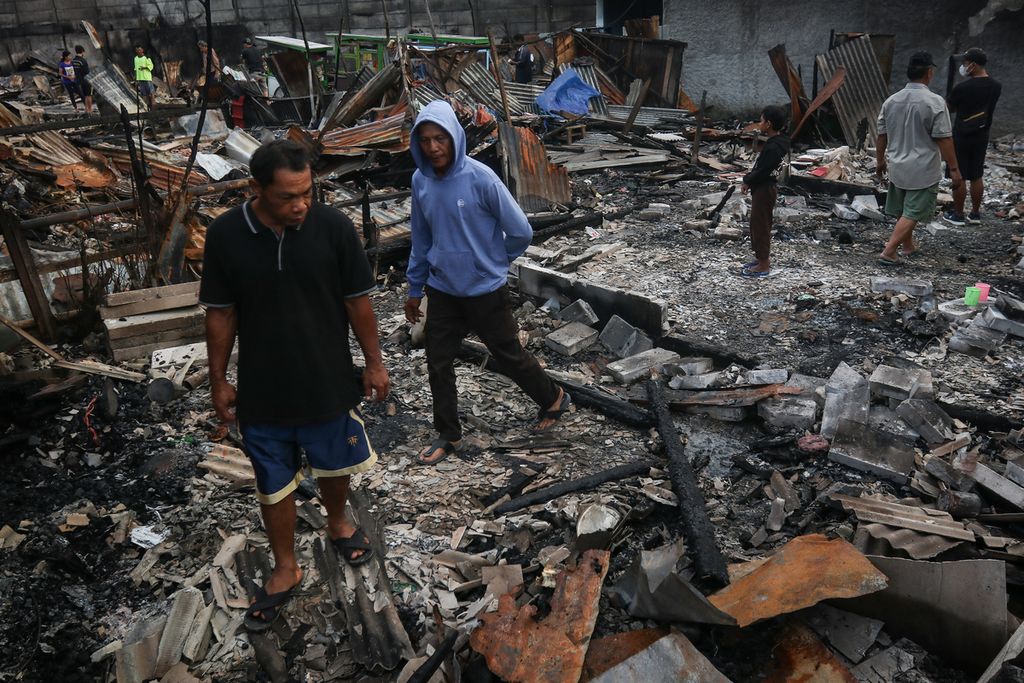 Four  men pass through the rubble of a burnt house on Jalan Tanah Merah Bawah, Rawa Badak Selatan, Koja, North Jakarta, Saturday (4/3/2023).