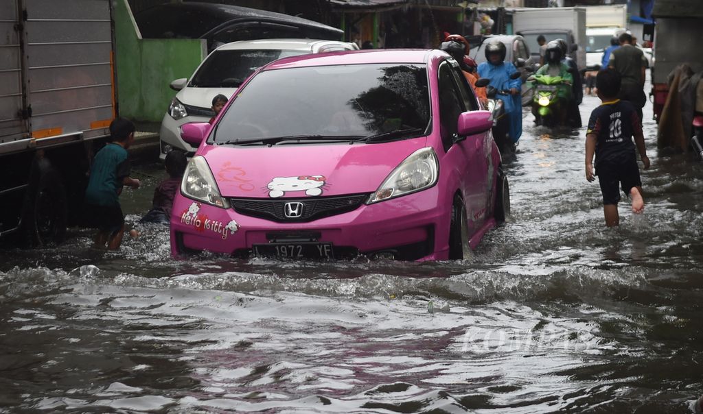 Sebuah mobil melewati banjir di Jalan Jagir Wonokromo Wetan, Surabaya, Selasa (11/1/2022). Hujan yang terjadi tidak beberapa lama sebabkan banjir di jalan tersebut. 