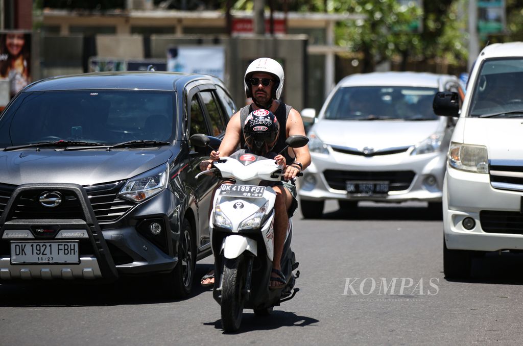 Turis asing mengenakan helm saat mengendarai sepeda motor di kawasan Kuta, Bali, Sabtu (18/3/2023). Sepeda motor sewaan menjadi pilihan oleh sebagian turis asing sebagai transportasi selama wisata di Bali karena berbagai alasan, seperti berbiaya murah dan praktis.