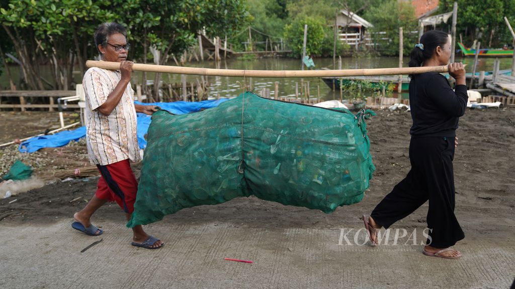 Two scavengers carry plastic waste in Pantai Mekar Village, Muaragembong District, Bekasi Regency, West Java, Thursday (27/10/2022).