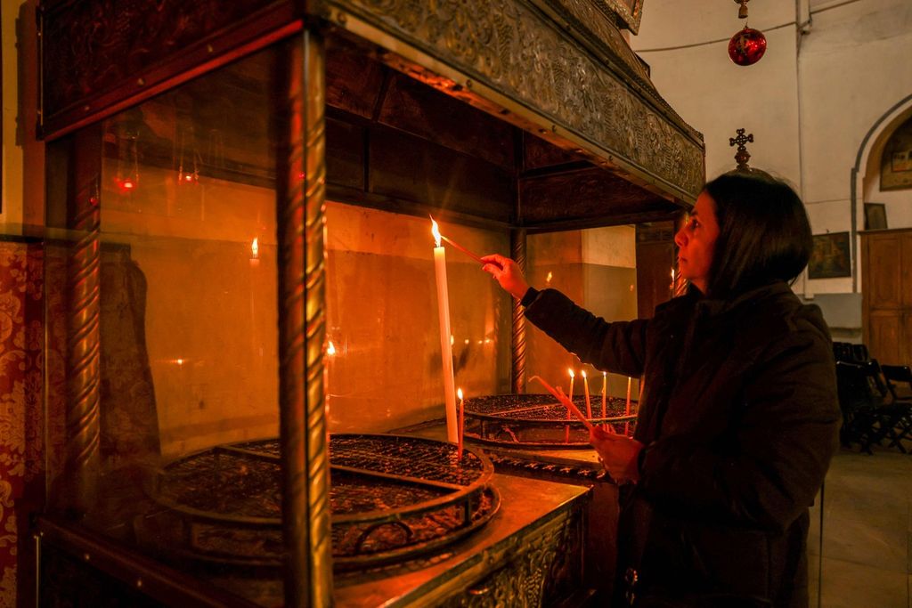 Seorang pengunjung menyalakan lilin di dalam Gereja Nativity di Bethlehem, wilayah pendudukan Tepi Barat, Rabu (13/12/2023). 