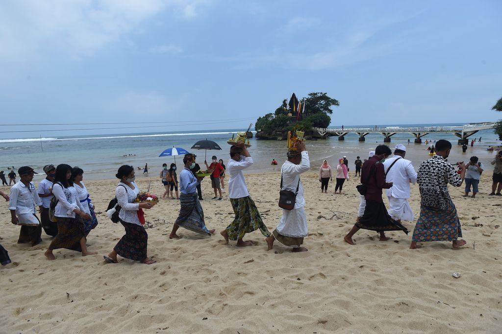 Umat Hindu berjalan beriringan melewati pantai dalam rangka Upacara Melasti di Pantai Balekambang, Kabupaten Malang, Jawa Timur, Kamis (11/3/2021). Upacara dilakukan sebagai bentuk pembersihan diri menjelang Hari Raya Nyepi. 