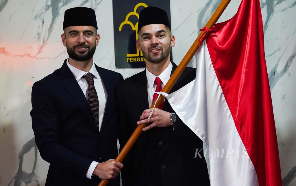 Dua pemain sepak bola naturalisasi Jordi Amat (kiri) dan Sandy Walsh memegang bendera Merah Putih seusai melakukan pengambilan sumpah janji setia sebagai warga negara Indonesia kedua pemain sepak bola tersebut di Kantor Wilayah Kementerian Hukum dan HAM DKI Jakarta, Jakarta, Kamis (17/11/2022). 