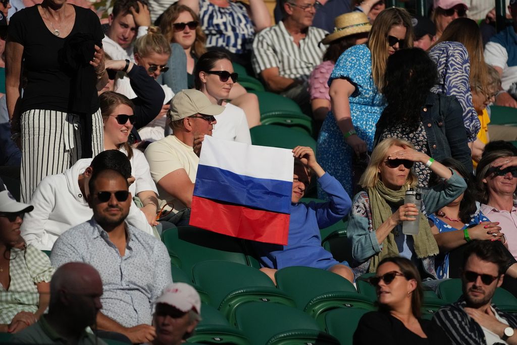 Penonton membentangkan bendera Rusia saat menyaksikan Daniil Medvedev (Rusia) melawan Marin Cilic (Kroasia) pada laga babak ketiga tunggal putra turnamen Wimbledon di London, Inggris, Sabtu (3/7/2021) lalu. Tahun ini, petenis Belarus dan Rusia, seperti Medvedev, tidak bisa tampil di Wimbledon menyusul agresi kedua negara itu ke Ukraina. 