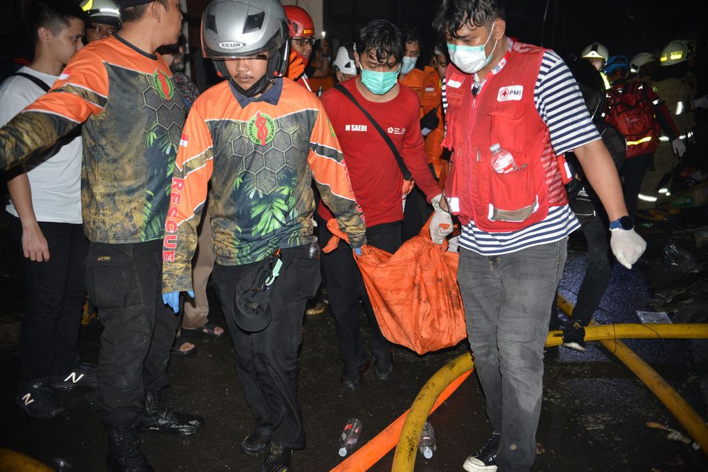 Petugas mengevakuasi korban kebakaran yang terjadi di Jalan Tanah Merah Bawah, Kecamatan Koja, Jakarta Utara, Jumat (3/3/2023). Kebakaran ini mengakibatkan belasan orang meninggal. Belum diketahui penyebab kebakaran tersebut. 