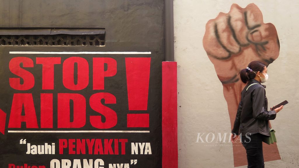 Warga melintas di dekat mural tentang AIDS di kawasan Ngawen, Sidomukti, Salatiga, Jawa Tengah, Rabu (30/6/2021). Melalui mural itu masyarakat diajak untuk berperan aktif mencegah penularan AIDS dan tidak memberi stigma negatif kepada pengidapnya.