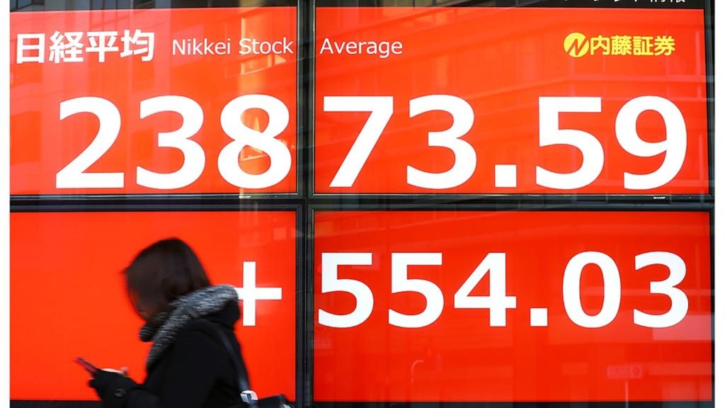 Pejalan kaki melewati papan informasi bursa yang menampilkan harga-harga saham di Bursa Efek Tokyo di Tokyo, Jepang, Kamis (6/2/2020). Tekanan inflasi secara global membayangi animo para pelaku pasar di pasar keuangan. 