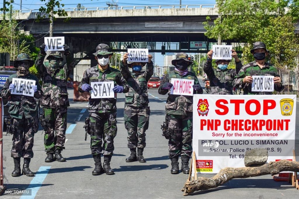  Aparat memegang plakat yang mengingatkan warga untuk tetap tinggal di rumah di tengah penyebaran Covid-19 di Manila, Filipina, pada 31 Maret 2020. 