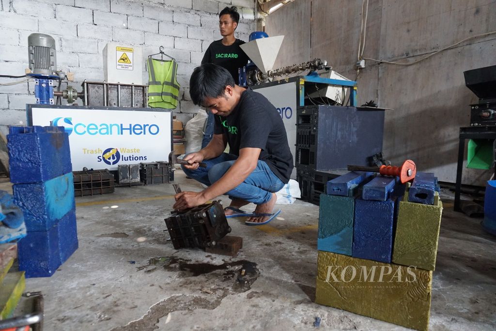 Jemsi Indra Yandi, tenaga staf operasional Baciraro Recycle, membuka cetakan batako plastik hasil daur ulang di studio daur ulang Baciraro Recycle di Tondano Timur, Minahasa, Sulawesi Utara, Kamis (9/6/2022). Satu batako memiliki berat 0,7-1,5 kilogram.