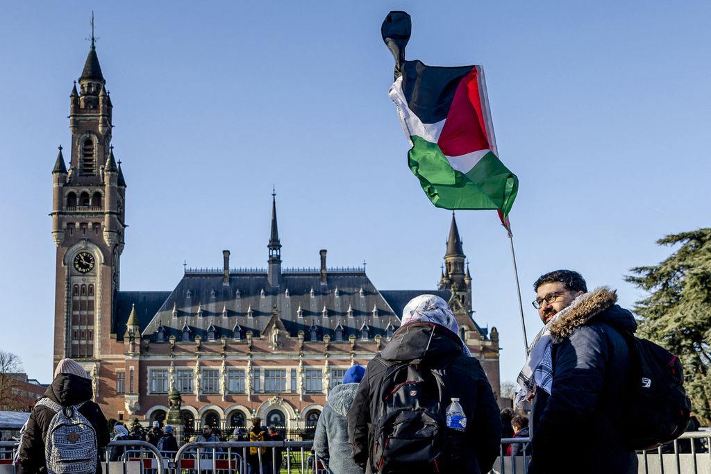 Seorang demonstran mengibarkan bendera Palestina di depan Istana Perdamaian menjelang putusan Mahkamah Internasional (ICJ) dalam kasus genosida terhadap Israel, yang diajukan oleh Afrika Selatan, di Den Haag pada 26 Januari 2024.