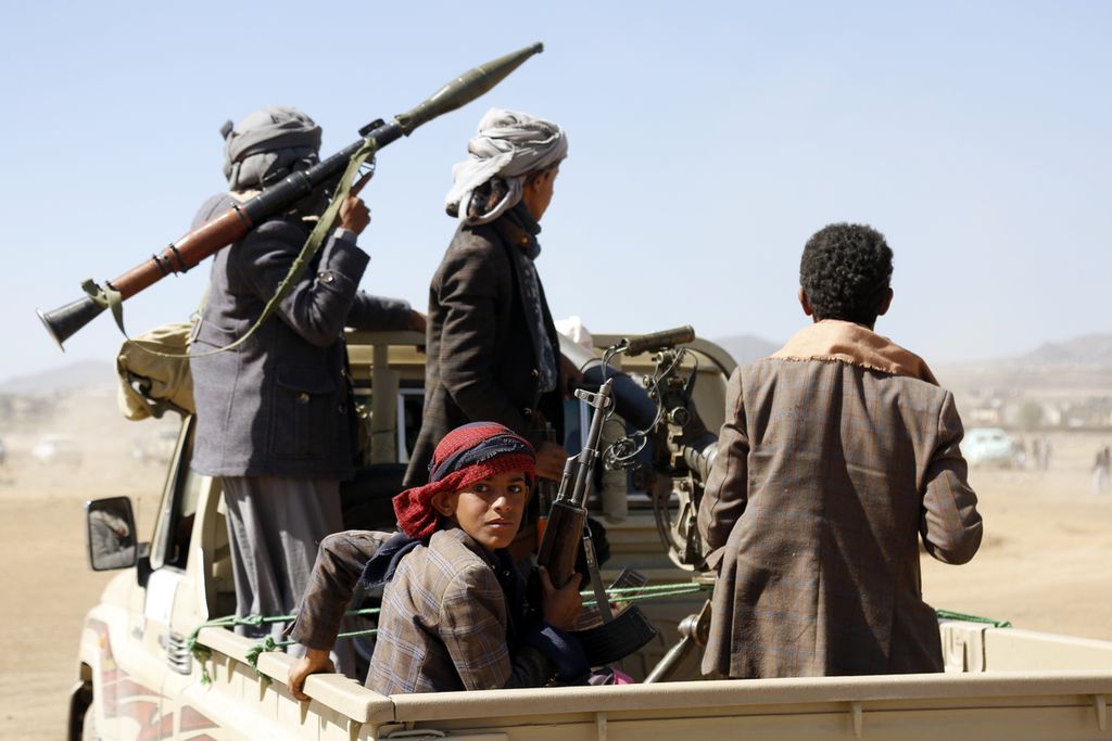 Anggota kelompok Houthi dengan membawa sejumlah persenjataan menaiki mobil bak terbuka di dekat kota Sana’a, Yaman, Minggu (14/1/2024).