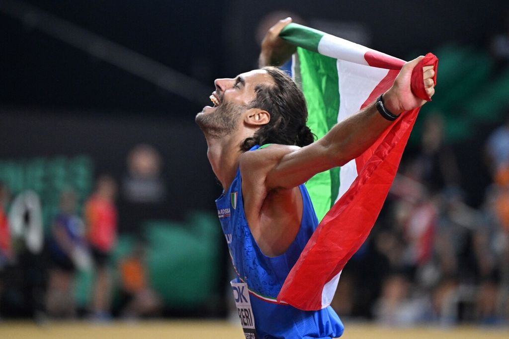 Gianmarco Tamberi membentangkan bendera Italia berlari merayakan kemenangannya di final loncat tinggi putra dalam Kejuaraan Dunia Atletik 2023 di Budapest, Hongaria, Rabu (23/8/2023) dini hari WIB. 