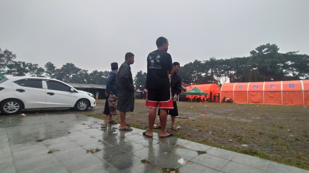 Sejumlah warga berbincang-bincang di depan tenda pengungsian Taman Prawatasari Cianjur, Jawa Barat, Senin (28/11/2022). Mereka tidak memedulikan hujan yang sore itu melanda.