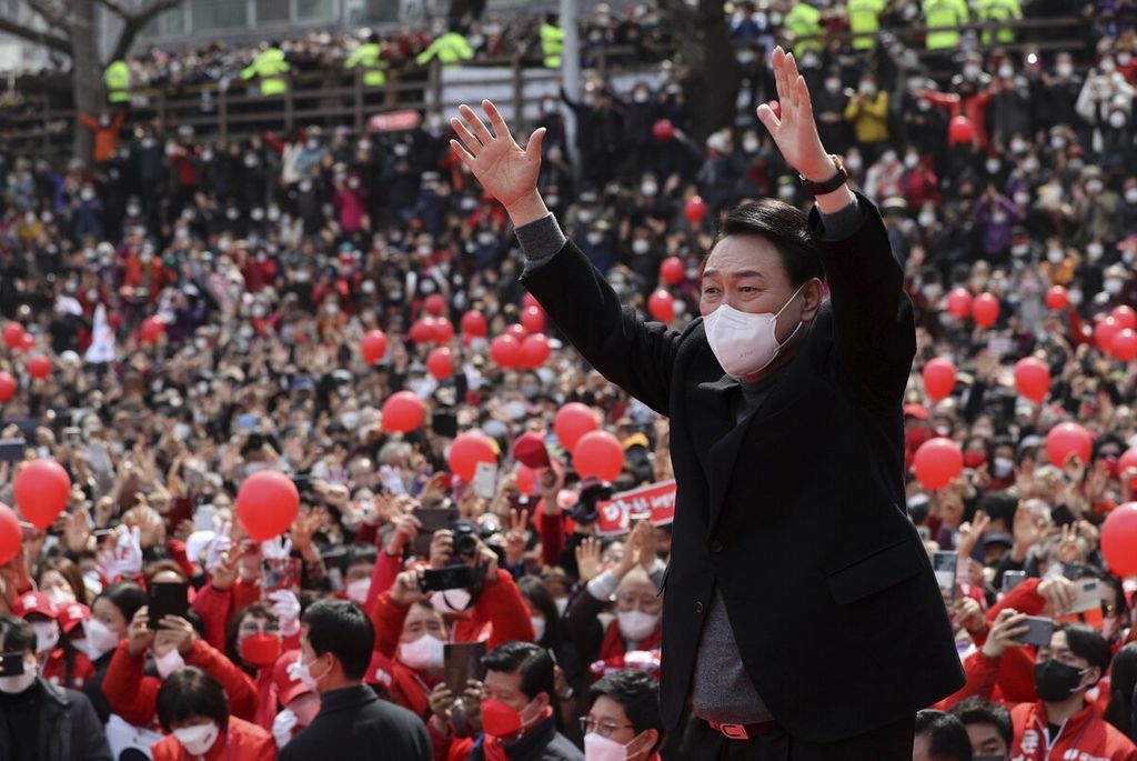 Yoon Suk-yeol, kandidat presiden dari oposisi utama Partai Kekuatan Rakyat, mengangkat tangannya saat kampanye pemilihan presiden di Busan, Korea Selatan, Selasa (8/3/2022). Yoon Suk-yeol adalah mantan jaksa agung yang bergabung dengan partai politik pada tahun lalu. 