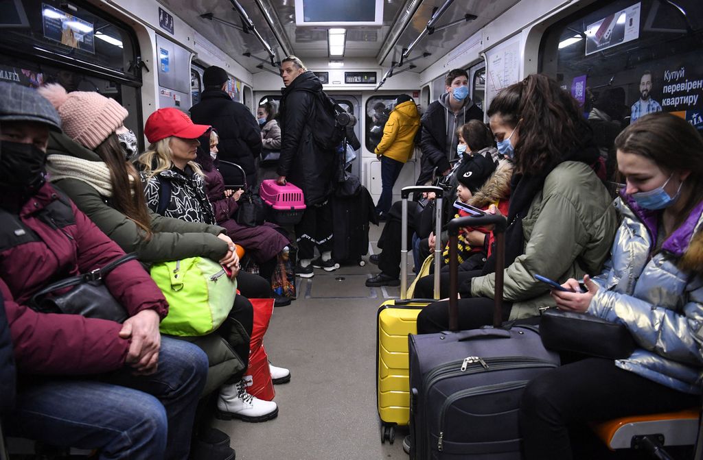 Orang-orang, beberapa membawa tas dan koper, duduk di metro di Kiev pada pagi hari 24 Februari 2022. Sirene serangan udara terdengar di pusat kota Kiev hari ini ketika kota-kota di seluruh Ukraina terkena apa yang dikatakan pejabat Ukraina sebagai serangan rudal dan artileri Rusia.