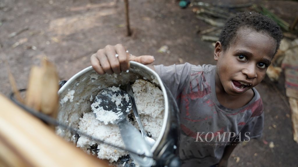 Seorang anak bersiap menghabiskan nasi di bivak di Distrik Animha, Kabupaten Merauke, Papua, Rabu (9/11/2022). 