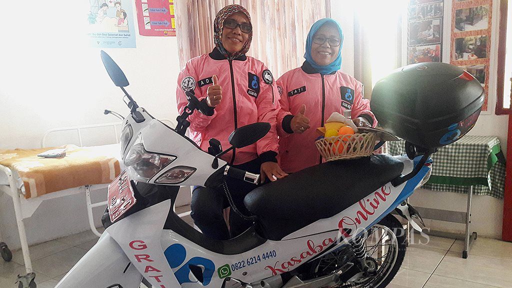 Kader Posyandu Wijayakusumah, Ade Hendrawati (49) dan Tati Mariyati (54), sedang berpose memakai jaket Kasaba Online dan motor operasional Kasaba Online di posyandu, Kelurahan Sekeloa, Kecamatan Coblong, Kota Bandung, Jawa Barat, Rabu (19/4).