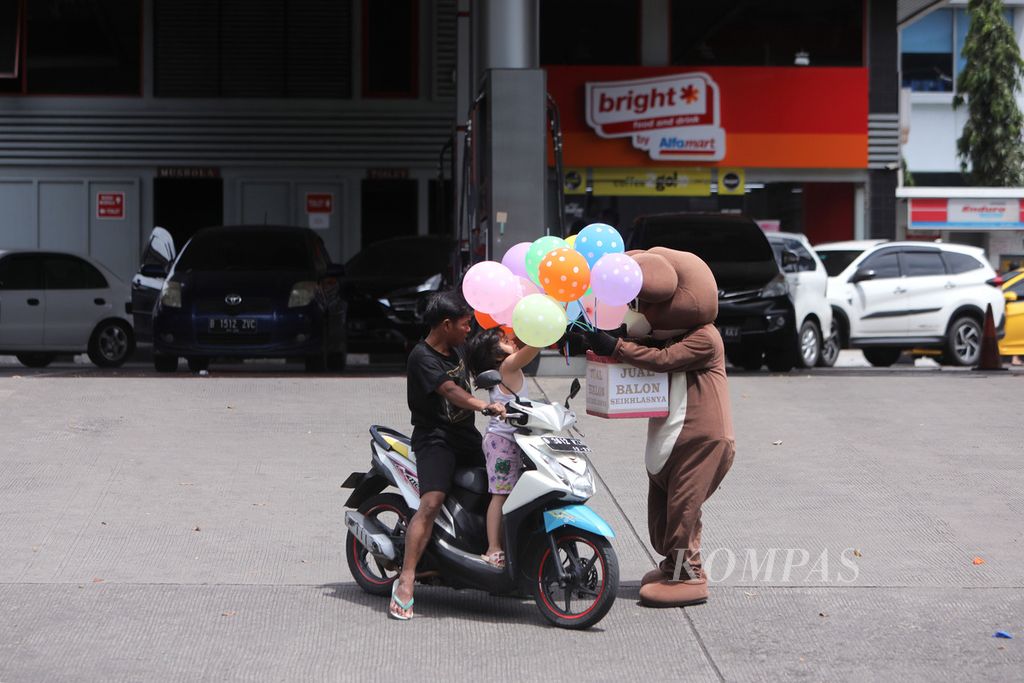 Pengendara sepeda motor membeli balon seusai mengisi bahan bakar minyak di sebuah SPBU di Jalan Boulevard BSD Timur, Tangerang Selatan, Banten, Minggu (3/4/2022). Kenaikan harga pertamax (RON 92) dari Rp 9.000 menjadi Rp 12.500 per liter membuat sejumlah konsumen beralih dari pertamax menjadi pertalite (RON 90) di harga Rp 7.650 per liter.