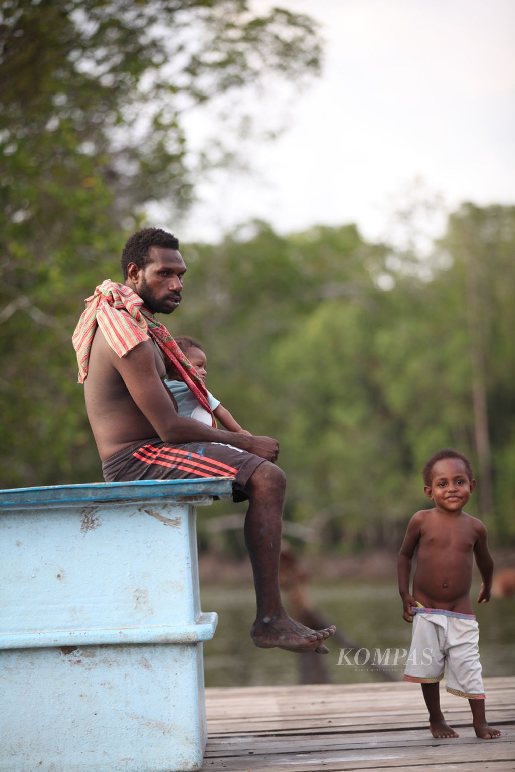 Seorang bapak di Papua sedang mengasuh anak