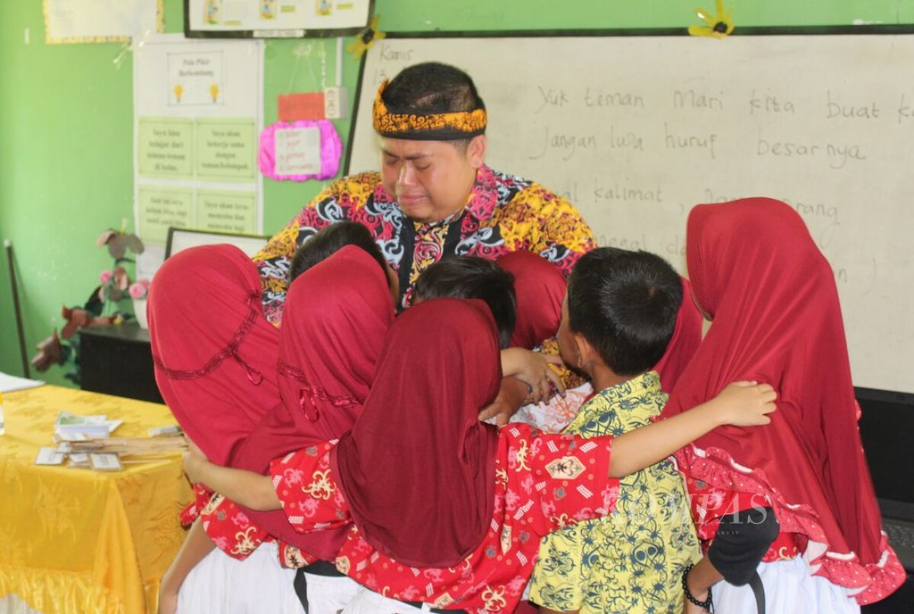 Sudarmuji (35), guru kelas II Sekolah Dasar Negeri 026 Tanjung Selor, Kabupaten Bulungan, Kalimantan Utara, dikerubungi siswa-siswanya, Kamis (13/4/2023).