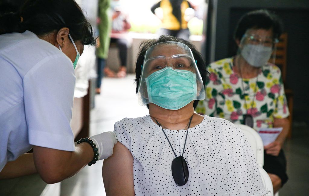 Petugas menyuntikkan vaksin Covid-19 dosis pertama ke warga lansia di Sekolah Cinta Kasih Tzu Chi, Cengkareng, Jakarta Barat, Rabu (24/2/2021). Warga lansia yang telah menerima suntikan vaksin dosis pertama ini akan kembali menjalani vaksin dosis kedua pada 24 Maret 2021. Warga lansia termasuk ke dalam kelompok rentan terhadap penularan Covid-19 sehingga mendapat prioritas vaksinasi.