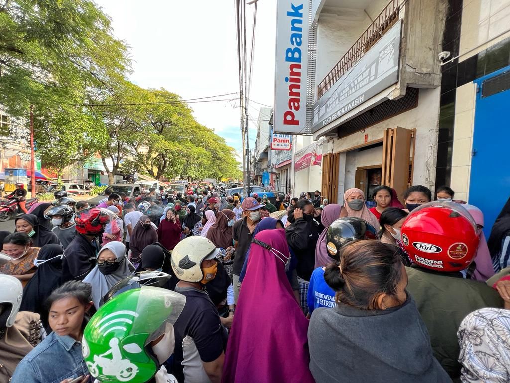 Warga berkerumun di depan salah satu toko di Jalan Veteran, Makassar, Sulawesi Selatan, Jumat (25/3/2022), yang menjual minyak goreng curah seharga Rp 15.500 per liter. Hingga kini minyak goreng masih langka dan mahal.