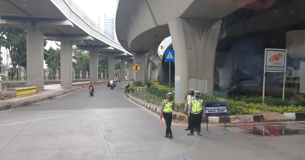 Beberapa polisi mengamankan pintu masuk menuju Jalan Gatot Subroto yang baru menerapkan aturan ganjil genap, Senin (25/10/2021) sore.