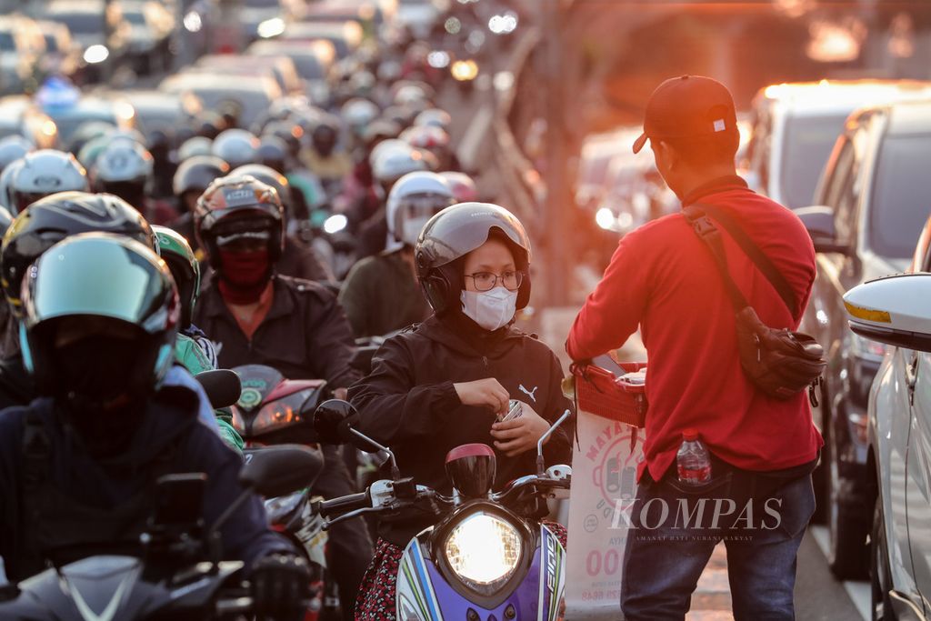 Pengendara sepeda motor membeli jajanan yang dijajakan pedagang keliling di tengah kemacetan di Jalan Gatot Subroto, Jakarta, Rabu (9/8/2023). Macet dan polusi udara masih menjadi permasalahan yang tak kunjung selesai di Jakarta. Mengutip dari data IQAir, indeks kualitas udara Jakarta tertinggi pada hari ini mencapai angka 165. Jumlah kendaraan yang naik setiap tahun pun menambah buruknya kemacetan di Jakarta. Badan Pusat Statistik (BPS) mencatat, jumlah kendaraan di Jakarta pada 2022 mencapai 26,3 juta kendaraan. 