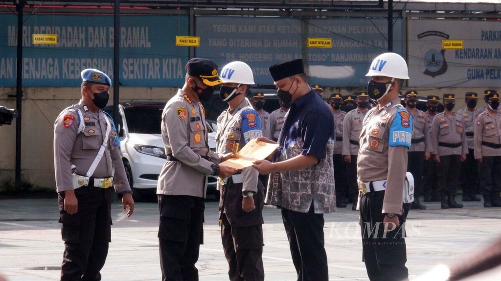 Kepala Kepolisian Resor Kota Banjarmasin Komisaris Besar Sabana Atmojo Martosumito (kiri) menyerahkan surat keputusan pemberhentian tidak dengan hormat (PTDH) kepada Bripka Bayu Tamtomo (kanan) dalam upacara PTDH di lapangan Polresta Banjarmasin, Kalimantan Selatan, Sabtu (29/1/2022).