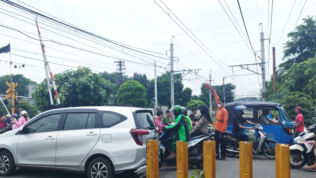 Harwanto (27) mengatur kendaraan seusai kereta melintas di pelintasan Jalan Jembatan Besi Raya, Kecamatan Tambora, Jakarta Barat, Selasa (8/2/2023).