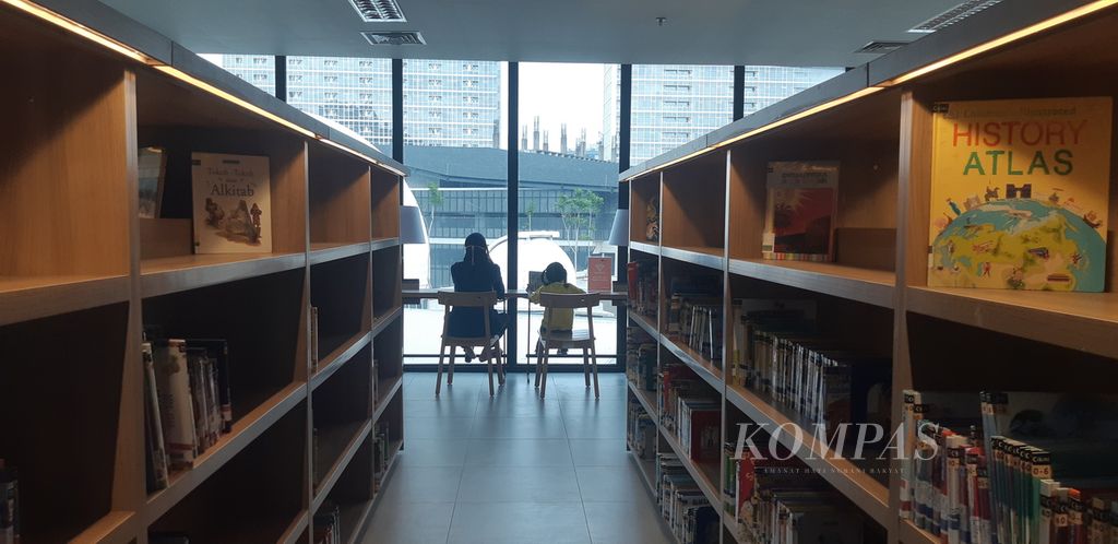 Two visitors read on one side of the floor at the Jakarta Library, in Cikini, Central Jakarta, Monday (29/8/2022).