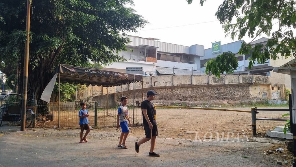 Seorang bapak berjalan bersama dua putranya melintas di lokasi yang dulu berdiri mes pemain Persema Malang di Klojen, Kota Malang, Jawa Timur, Senin (24/7/2023). Bangunan itu dibongkar pada Januari 2022.