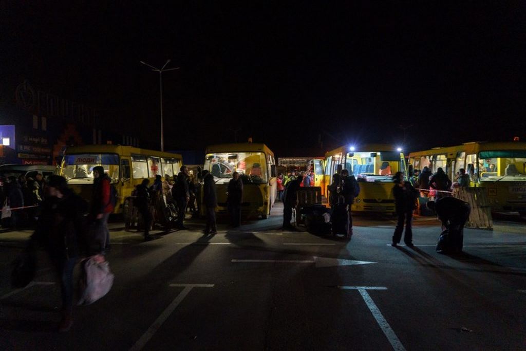 Penumpang turun dari konvoi 30 bus yang membawa pengungsi dari Mariupol dan Melitopol saat tiba di Zaporizhzhia, 1 April 2022.