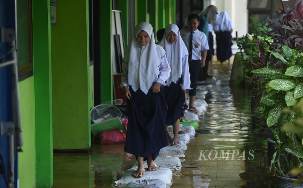 Siswa melewati karung berisi pasir untuk menghindari banjir di SMP Negeri 2 Tanggulangin, Sidoarjo, akhir Januari 2020.