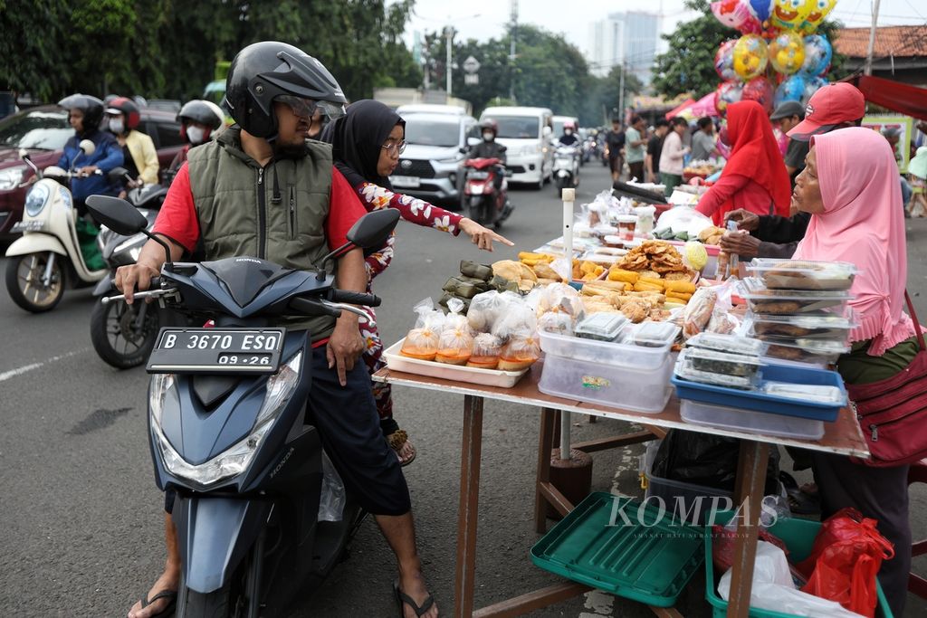 Pengendara sepeda motor membeli takjil di salah satu pedagang di Jalan Panjang, Kebon Jeruk, Jakarta, Selasa (26/3/2024).