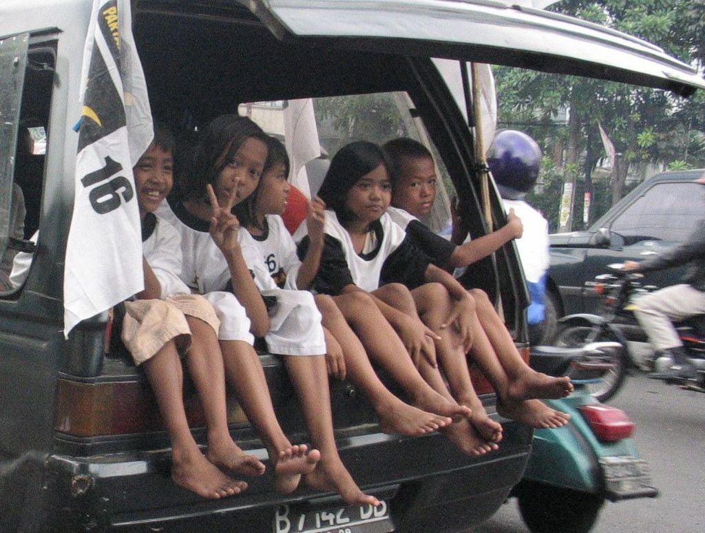 Sejumlah anak sepulang sekolah tampak menikmati kegiatan kampanye putaran ke-3 Partai Keadilan Sejahtera (PKS) di Jakarta. Dengan bertelanjang kaki, mereka ikut dalam bagasi sebuah mobil yang melintas di Jalan Mampang Prapatan Raya, Jakarta Selatan, Selasa (30/3/2004).