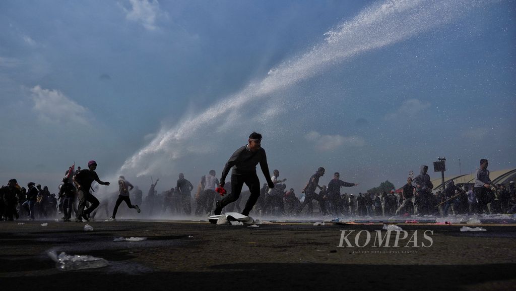Para pemeran demonstran menghindari semprotan <i>water canon </i>TNI ketika digelar simulasi pengamanan dalam Apel Gelar Pasukan Pengamanan Pemilu Tahun 2024 di Lanud Halim Perdanakusumah, Jakarta, Kamis (1/2/2024). 