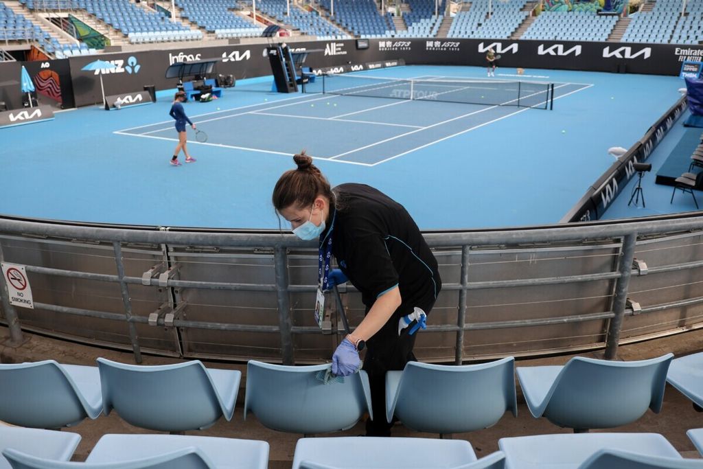 Pekerja membersihkan kursi penonton saat sesi pemanasan Australia Open di Melbourne, 4 Februari 2021.