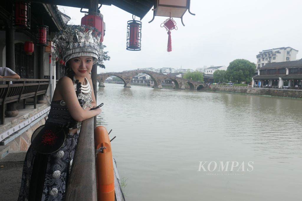Gadis lokal berpose dengan latar belakang Kanal Besar dan Jembatan Gongceng di Kota Tua Tangqi, Hangzhou, Provinsi Zhejiang, China, Jumat (22/9/2023). 