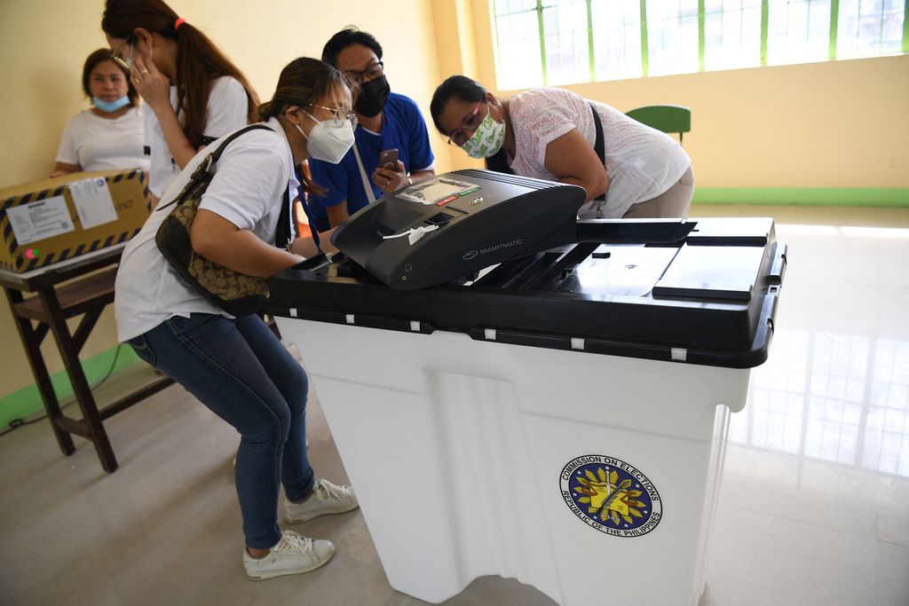 Petugas pemungutan suara dan sejumlah saksi dari setiap kandidat yang bertarung pada pemilihan umum Filipina memeriksa nomor seri mesin suara di sebuah tempat pemungutan suara di kota Manila, Rabu (4/5/2022). 