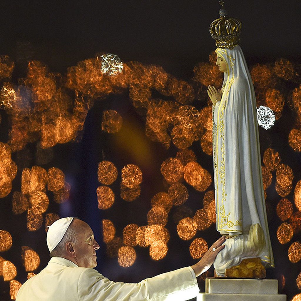 Paus Fransiskus memegang patung Santa Maria dari Fatima saat berlangsung pemberkatan lilin dari Kapel Penampakan di Fatima, Portugal, Jumat (12/5).   