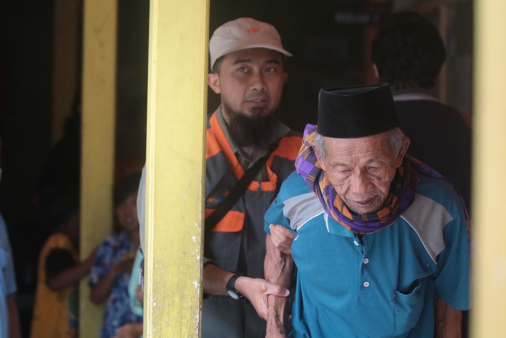 Seorang relawan di SDN Supit Urang 04, Desa Supit Urang, Pronojiwo, Lumajang, terlihat membantu warga lansia pergi ke kamar kecil. Kelompok lansia merupakan kelompok rentan terkena parkinson.
