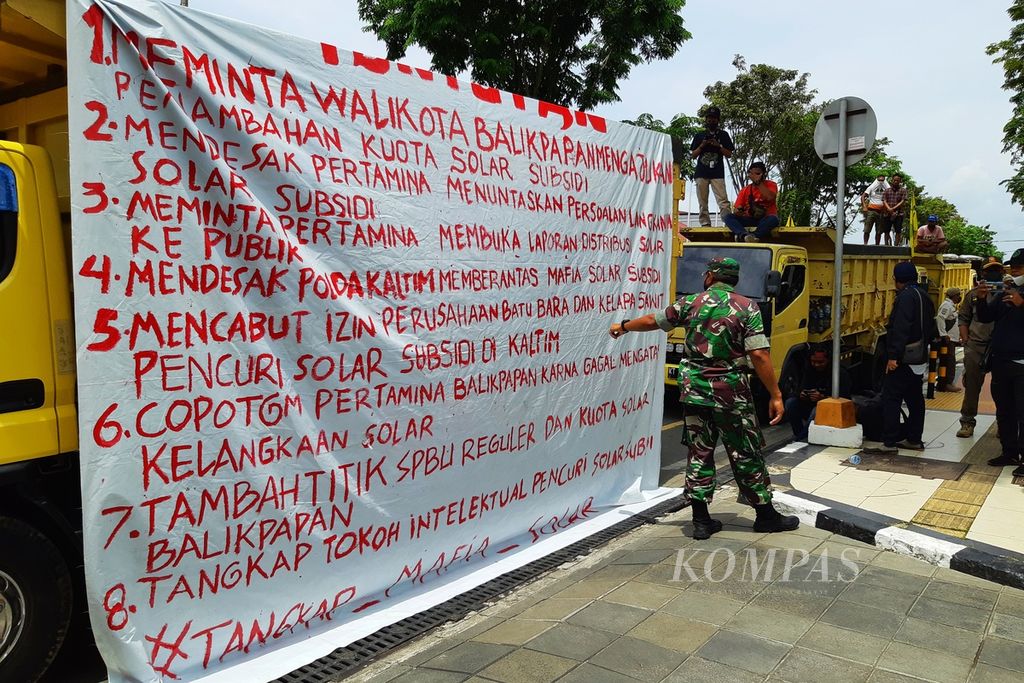 Sopir truk membentangkan spanduk tuntutan di bak truk saat berunjuk rasa di depan Kantor Wali Kota Balikpapan, Kalimantan Timur, Rabu (30/3/2022). 