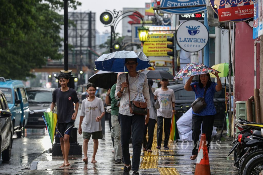 Sejumlah warga mengenakan payung saat berjalan di Jalan Margonda, Kota Depok, Jawa Barat, Sabtu (13/1/2024).