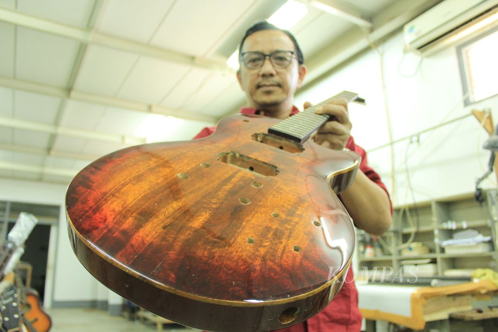 Musisi Muhammad Suar mmperlihatkan gitar buatan Genta yang menggunakan bahan dari pohon mangga asal Indramayu di Bandung, Jawa Barat, Senin (6/3/2023).