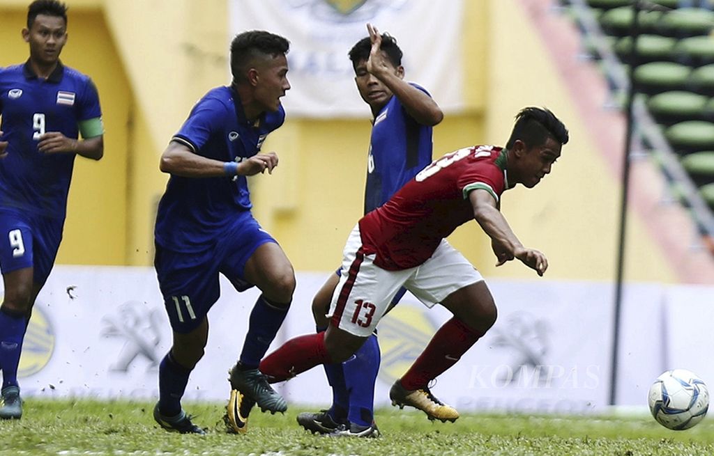 Pemain tim nasional  sepak bola Indonesia U-22, Febri Hariadi (13), berusaha lepas dari pemain Thailand dalam laga babak penyisihan Grup B SEA Games Kuala Lumpur 2017 di Stadion Shah Alam, Selangor, Malaysia, Selasa (15/8). Laga berakhir 1-1.