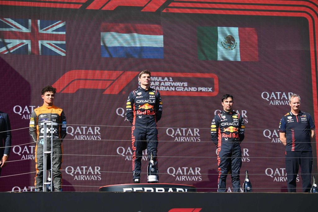 Para pemenang Grand Prix Formula 1 seri Hongaria (kiri ke kanan), Lando Norris (McLaren) yang finis kedua, Max Verstappen (Red Bull) yang finis pertama, dan Sergio Perez (Red Bull) yang finis ketiga, serta kepala mekanik Red Bull Paul Monaghan, berdiri di podium Sirkuit Hungaroring, Minggu (23/7/2023). 