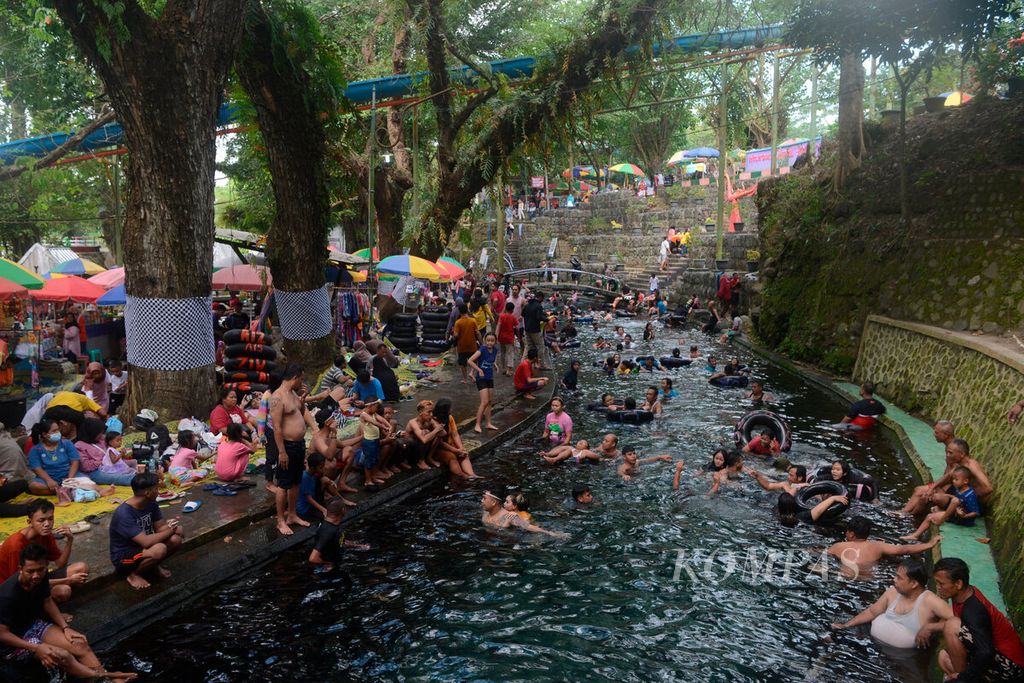 Suasana liburan warga dengan berenang dan bermain air di Umbul Cokro Tulung, Desa Cokro, Kecamatan Tulung, Kabupaten Klaten, Jawa Tengah, Selasa (3/5/2022). Keramaian pengunjung ini memberikan dampak besar bagi perekonomian warga setempat setelah dua tahun sepi karena pembatasan sosial. 